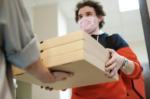 A man receiving his pizza from the meal delivery service.