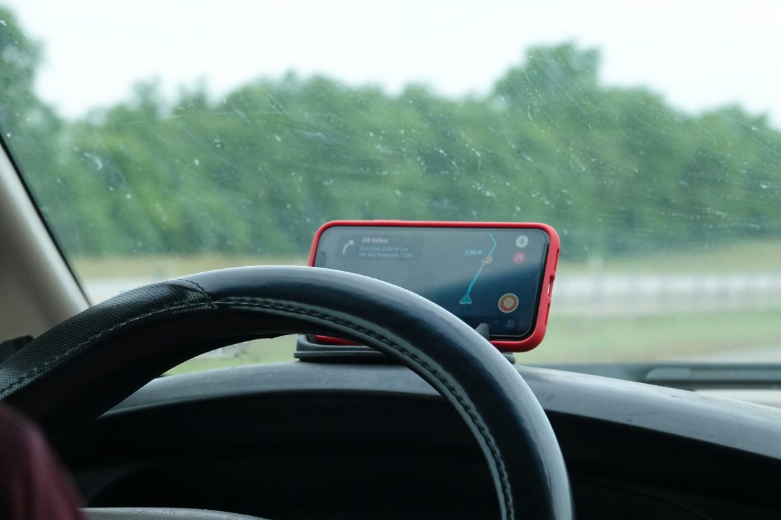 A person using one of the most essential travel apps, Waze for directions while driving.